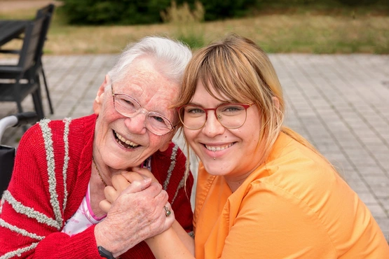 Pflegekraft und Bewohnerin lachen gemeinsam