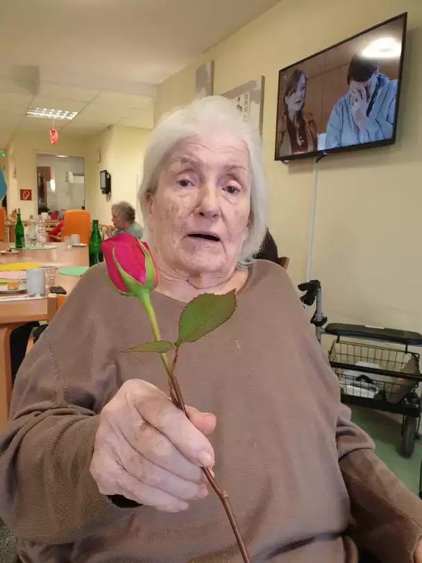 Seniorin mit Rose am Weltfrauentag in der avendi-Einrichtung Pflegeheim NECKARHAUS
