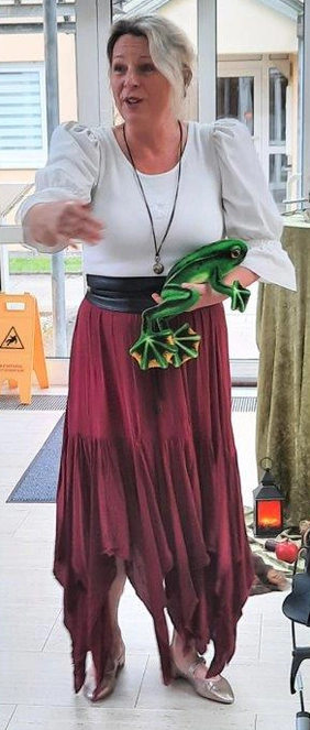 Die Märchenerzählerin hält eine Froschfigur in der Hand