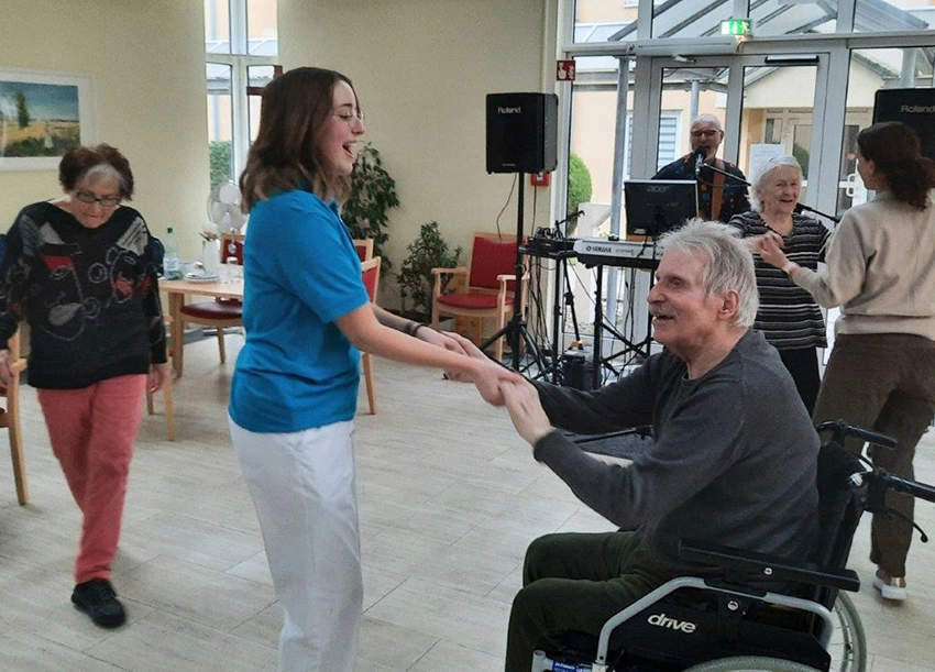 Mitarbeiterin tanzt mit Mann im Rollstuhl