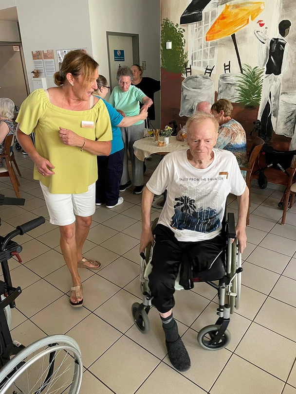 Mitarbeiterin tanzt mit Bewohner im Rollstuhl