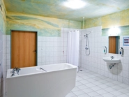 Weiß gekacheltes Pflegebad mit Badewanne und bodengleicher Dusche