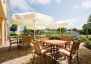 NECKARHAUS Terrasse mit Sonnenschirmen, Tischen und Stühlen, im Hintergrund Parkanlage und Häuser.