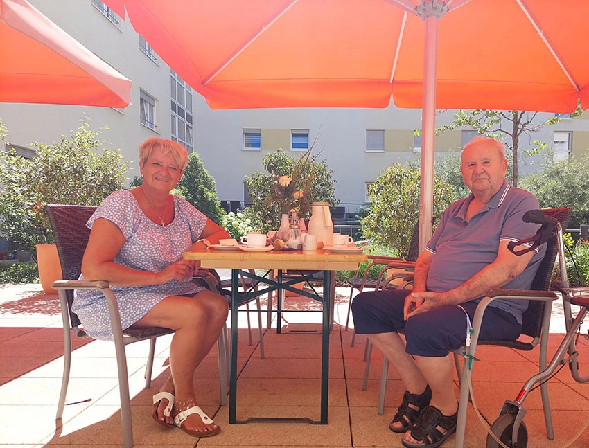 Eine Seniorin und ein Senior am Tisch auf der Terrasse