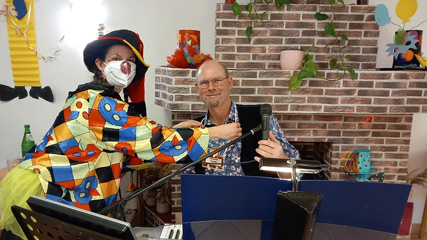 Mitarbeiterin, als Clown verkleidet, und Musiker am Keyboard