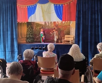 Publikum schaut auf Marionetten-Bühne