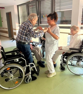 Mitarbeiterin hilft Bewohner aus dem Rollstuhl