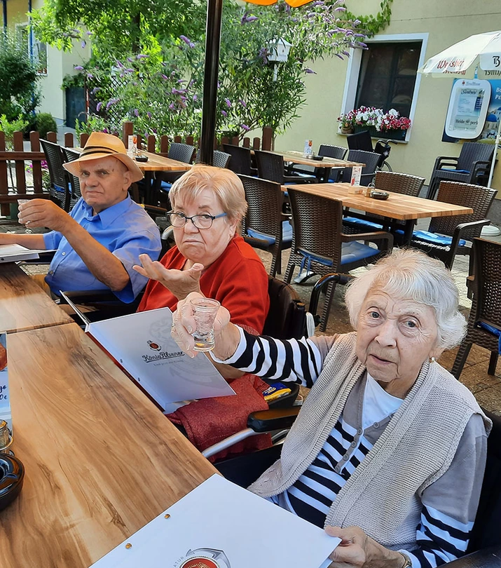 Senioren am Tisch unter einem Schirm auf der Terrasse