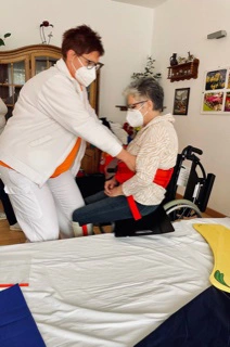 Pflegerin übt, eine Bewohnerin vom Rollstuhl aufs Bett umzulagern.
