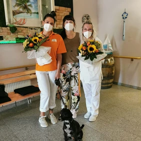 Heimleiterin Anke Rinne überreicht zwei Mitarbeiterinnen Blumen.