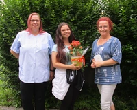 Heimleiterin Daniela Müller und eine Mitarbeiterin gratulieren Lisa Jendrzok zur bestandenen Prüfung.
