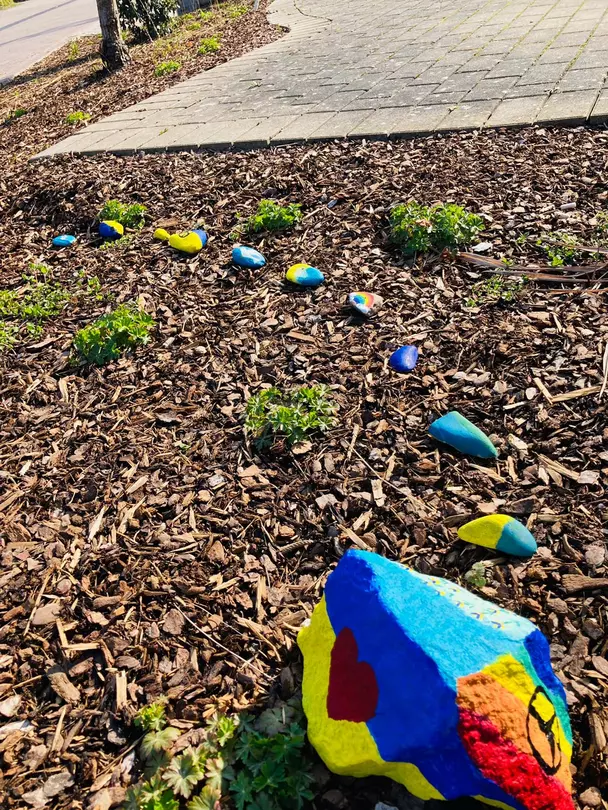 Eine Schlange aus gelben und blauen Steinen steht in der avendi-Einrichtung RHEIN-PFALZ-STIFT für Frieden, Solidarität und Zusammenhalt.