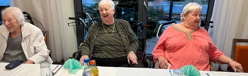 Seniorinnen und ein Senior am Tisch in der Cafeteria