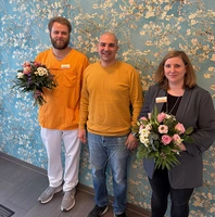 Tobias Kruse und Stefanie Beeken mit Blumen, dazwischen der Sprecher der Vertrauenspersonen Francesco Maniscalco