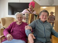 Bewohnerinnen der Seniorenresidenz ALTE MÜHLE schunkeln zur Musik von Akkordeonspieler Norbert Schremps.