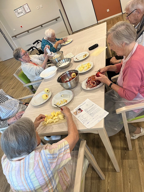 Seniorinnen und Senioren gemeinsam am Tisch, auf dem Backutensilien sind