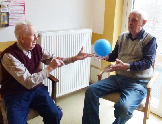 Zwei alte Männer werfen sich einen blauen Ball zu.