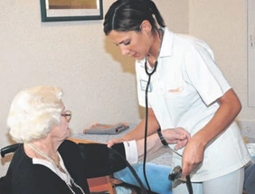 Pflegerin misst den Blutdruck einer älteren Dame