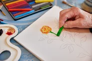 Die Hand einer Seniorin hält einen Stift. Sie malt.