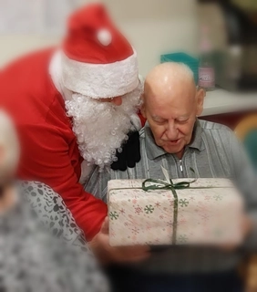 Der Nikolaus übergibt ein Geschenk an einen Bewohner