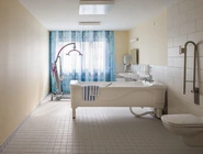 Pflegebad mit Badewanne, Lift und Fenster mit Vorhängen