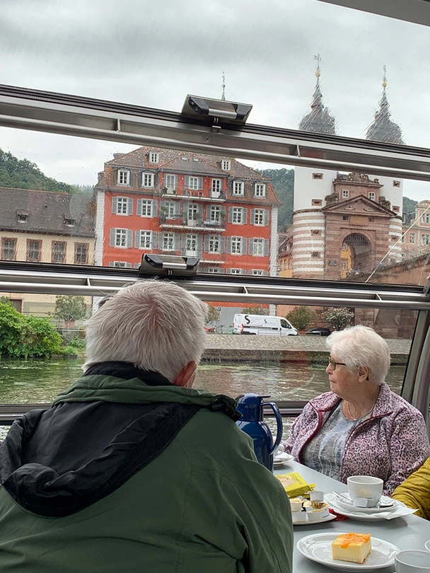 Bewohner und Bewohnerin blicken vom Schiff aus auf Heidelberg