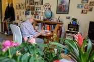 Ein Bewohner sitzt an seinem Schreibtisch. Blumen, Andenken und Bücher sind zu sehen.