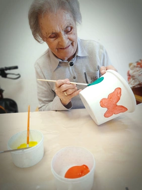 Seniorin bemalt Blumentopf im avendi-Pflegeheim Neckarhaus