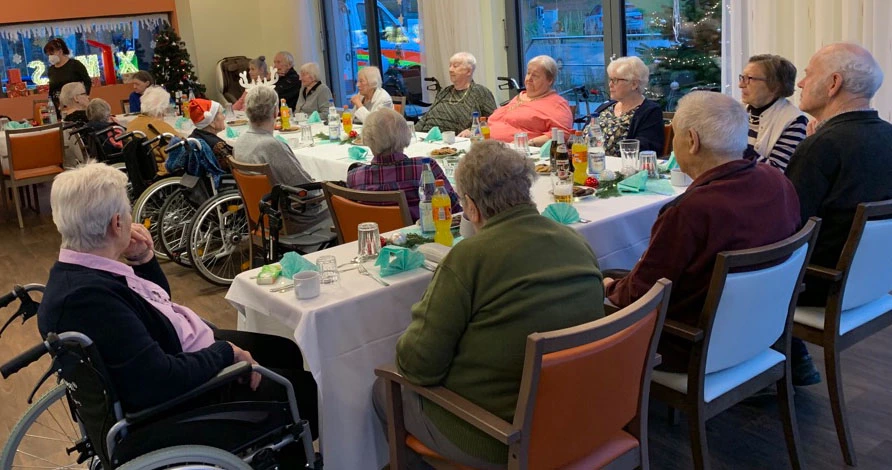 Seniorinnen und Senioren an einer langen gedeckten Kaffeetafel