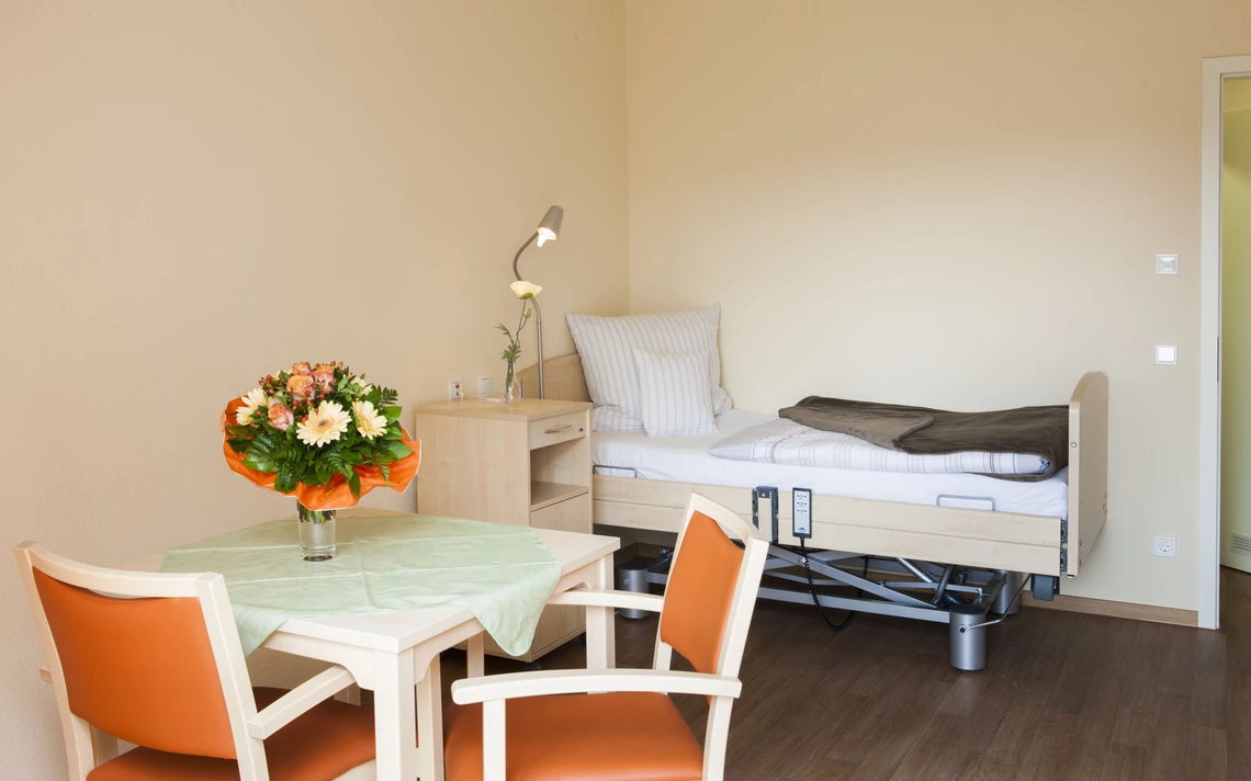 Centro Verde Einzelzimmer, Bett mit Bettschränkchen, Tisch mit Stühlen und Blumenvase