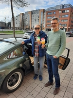 Bewohner und Herr Kuhse vor dem Porsche mit Drink in der Hand.