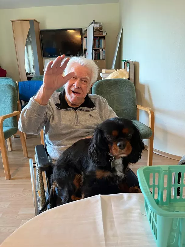 Bewohner im Sinsheimer avendi-Pflegeheim HAUS BURGBLICK hält Hund auf dem Schoß