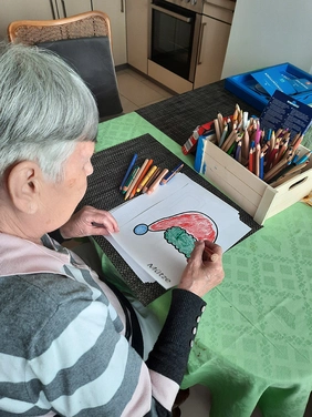 Eine Seniorin malt eine Zeichnung aus.
