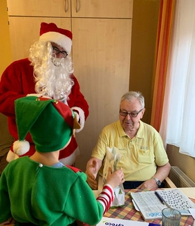 Weihnachtsmann und Elf verteilen Geschenke