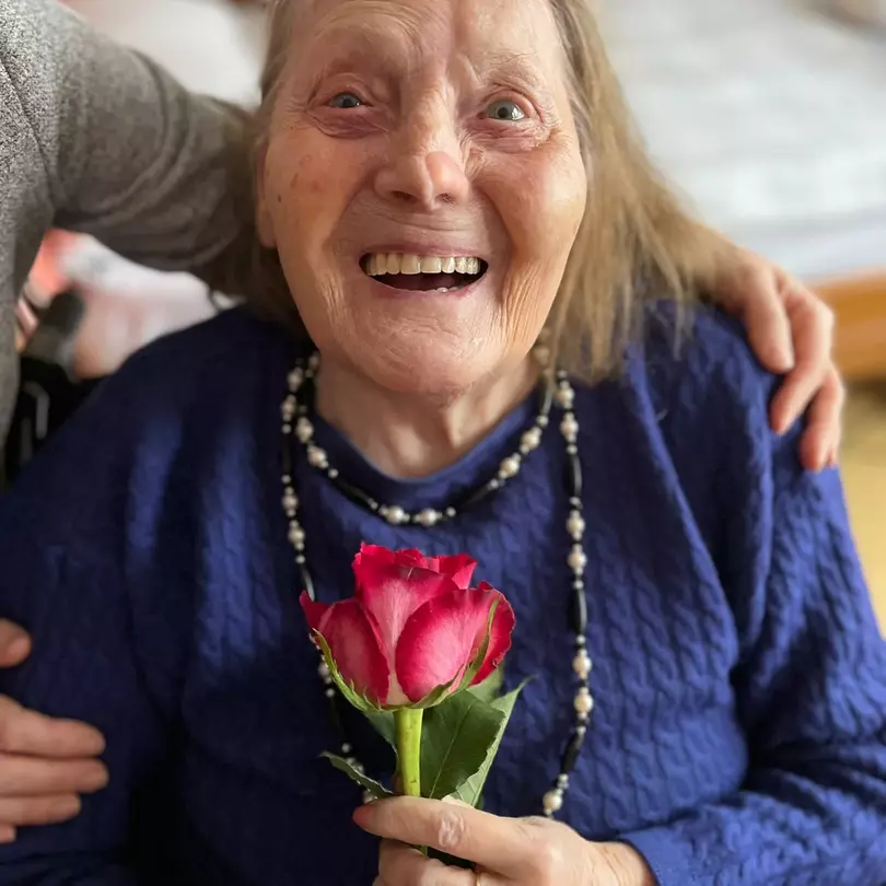 Seniorin mit Rose am Weltfrauentag 2023 in der avendi-Pflegeeinrichtung EDI-WOHNPARK.