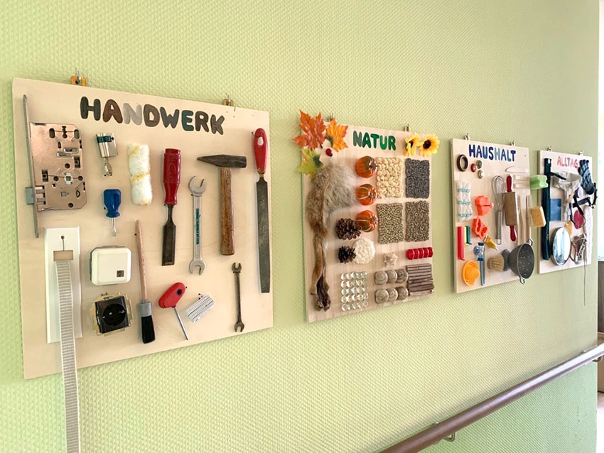An der Wand hängen einzelne Bilder, an denen Werkzeuge, Küchenutensilien und andere Gegenstände angebracht sind.
