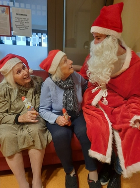 Der Nikolaus sitzt bei zwei Bewohnerinnen auf dem Sofa
