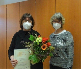 Heimleiterin Angelika Frey (r.) gratuliert Sylvia Brendel mit Blumen und Urkunde zum Dienstjubiläum.