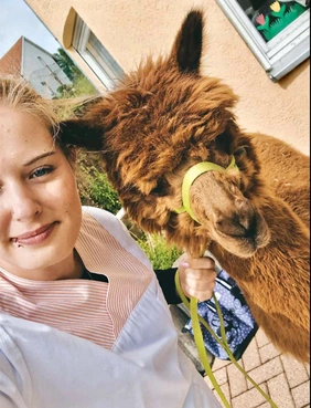 Mitarbeiterin macht Selfie mit Alpaka