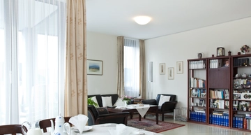 LanzCarré Pflege-Apartment mit Tisch im Vordergrund, Regalwand und Couch im Hintergrund