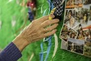 Eine Bewohnerin betastet eine Fühlwand bestehend aus Kunstrasen mit Bildern, Bändern, Tüchern und anderen Objekten