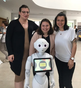 Schülerinnen und Praxisanleiterin mit Roboter