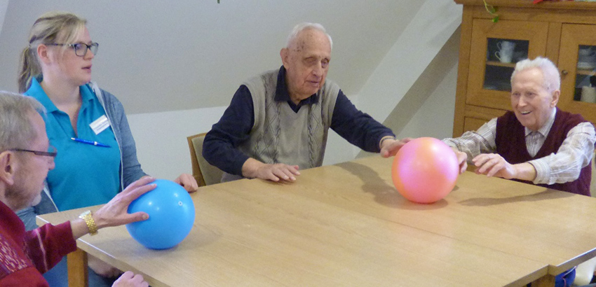 Senioren rollen zwei farbige Bälle über den Tisch.